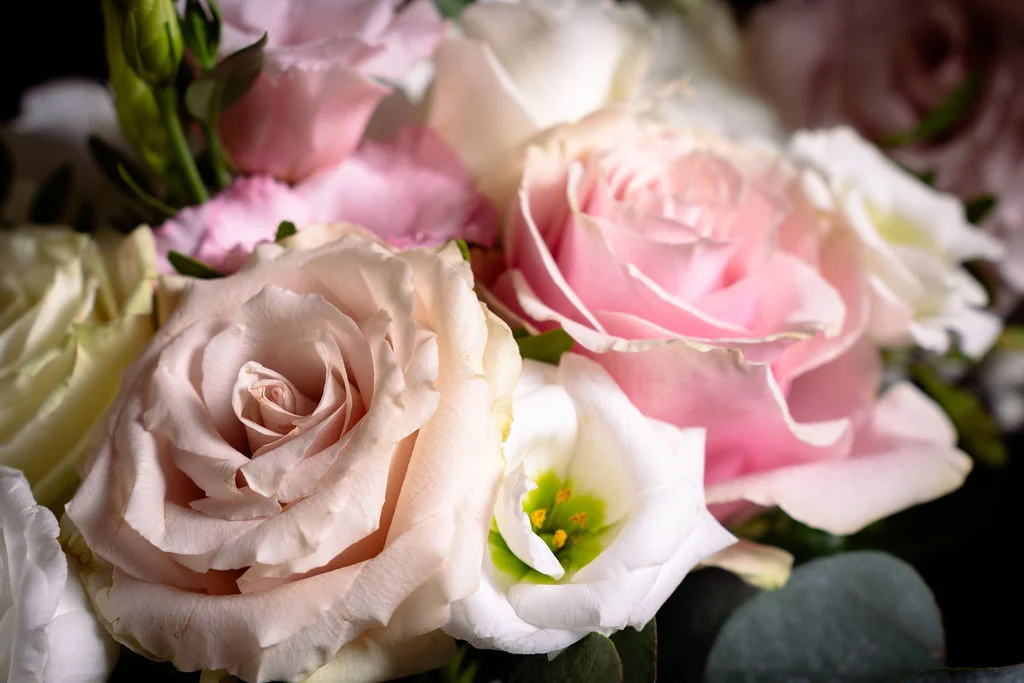 An exquisite macro close-up captures a romantic wedding bouquet featuring soft quicksand roses and delicate pink lisianthus with lush greenery.