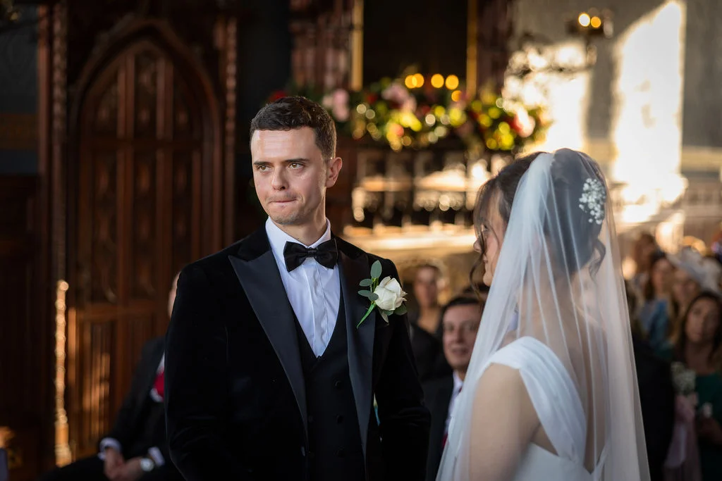 An emotional groom looks at his bride with tears in his eyes during their church wedding ceremony.