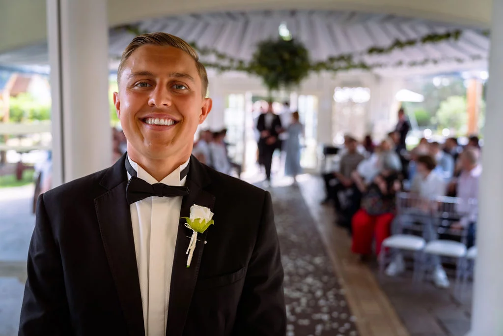 A man in a tuxedo smiles in front of an audience.