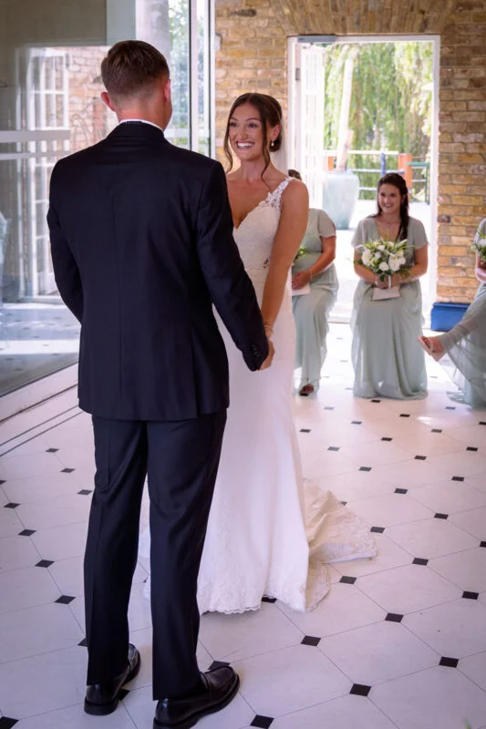 A bride and groom standing in front of a glass door.
