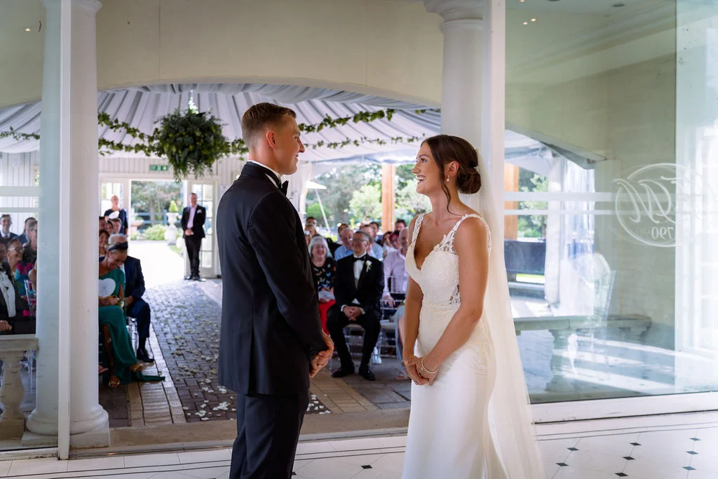 A bride and groom standing in front of a glass door.