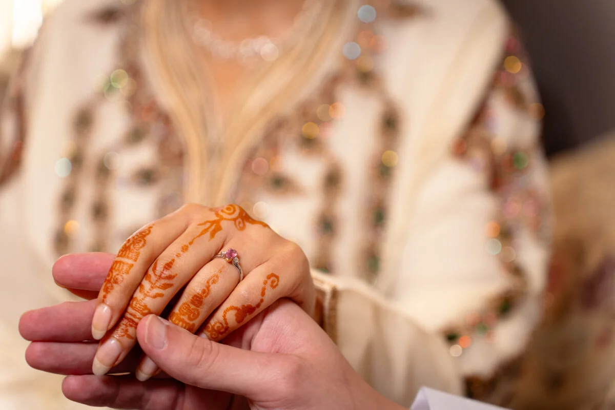 A woman holding a man's hand with henna on it.