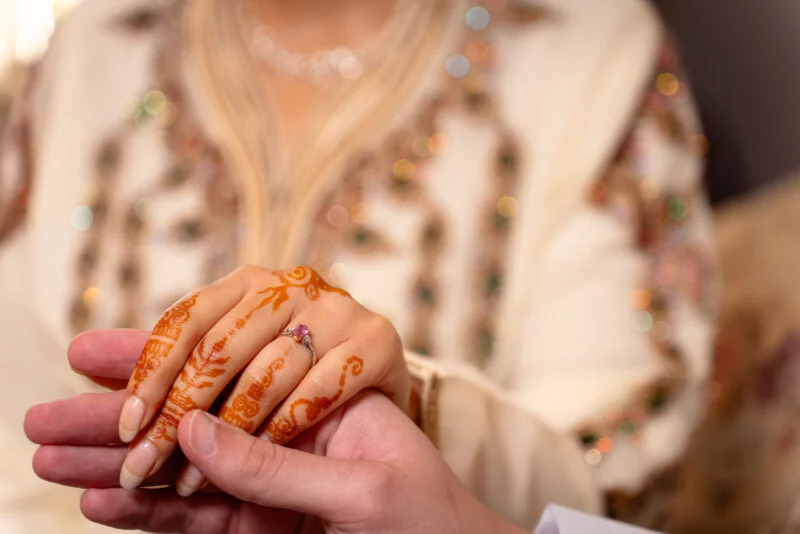 A woman holding a man's hand with henna on it.