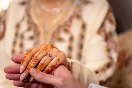 A woman holding a man's hand with henna on it.