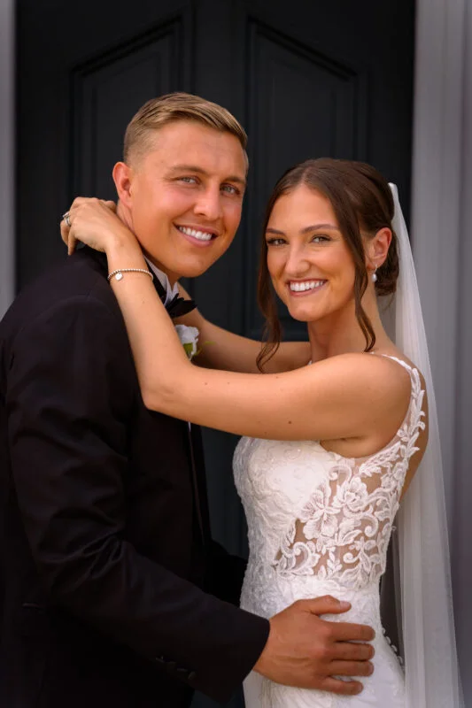 A bride and groom embracing in front of a black door.