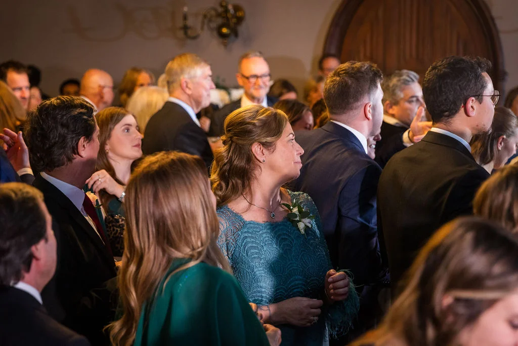 A candid group of wedding guests dressed in formal attire and teal tones mingle during the celebration.