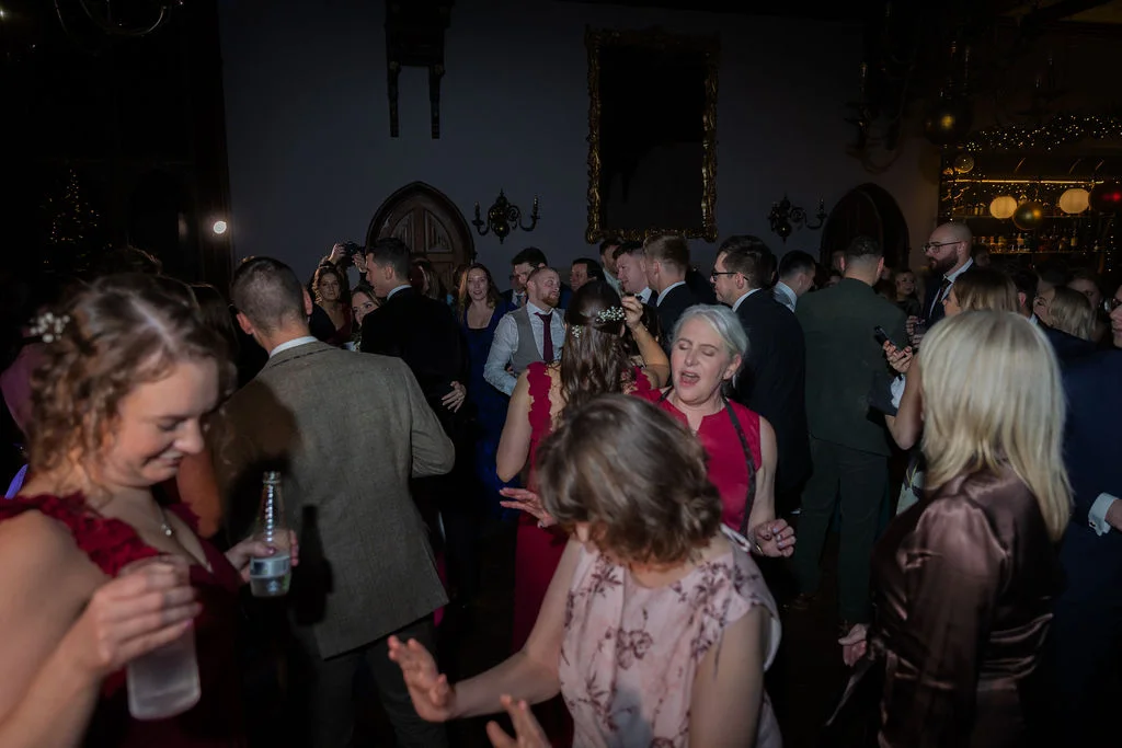 A lively group of wedding guests enjoying themselves on the dance floor in a warmly lit ballroom.