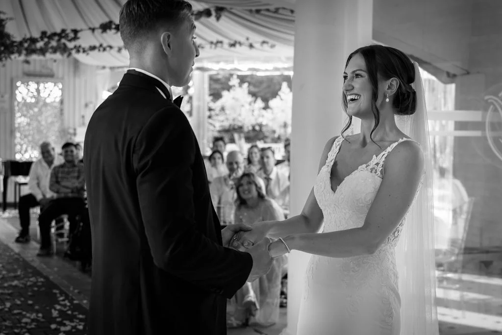A bride and groom smiling at each other during their wedding ceremony.