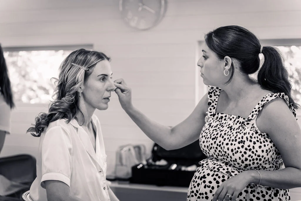 A bride having her makeup carefully applied by a makeup artist during the morning preparations.