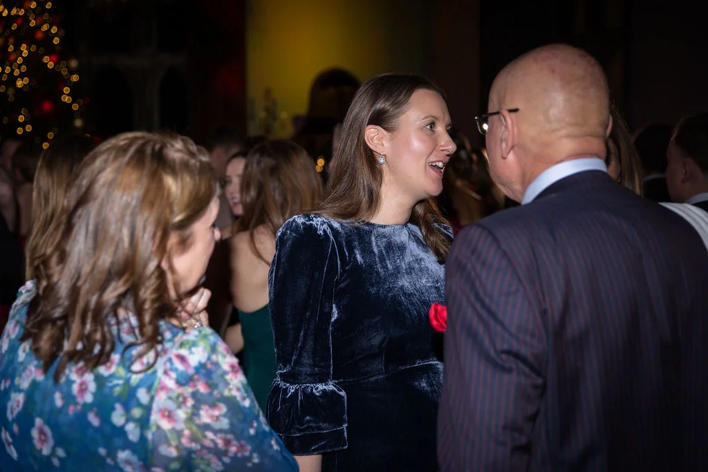 Guests mingle and chat during an evening wedding reception illuminated by warm fairy lights.