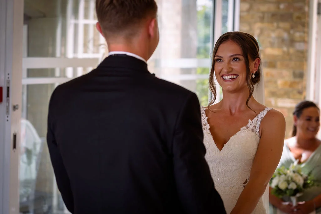 A bride and groom smile at each other during their wedding ceremony.