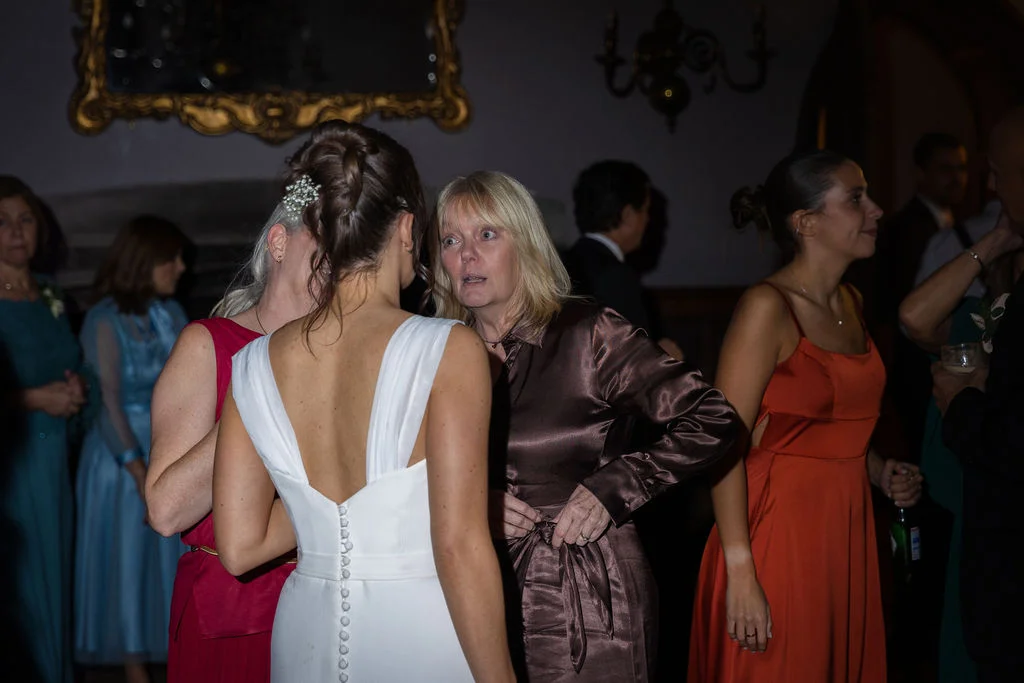 Wedding guests mingling inside an evening reception with guests chatting and observing.