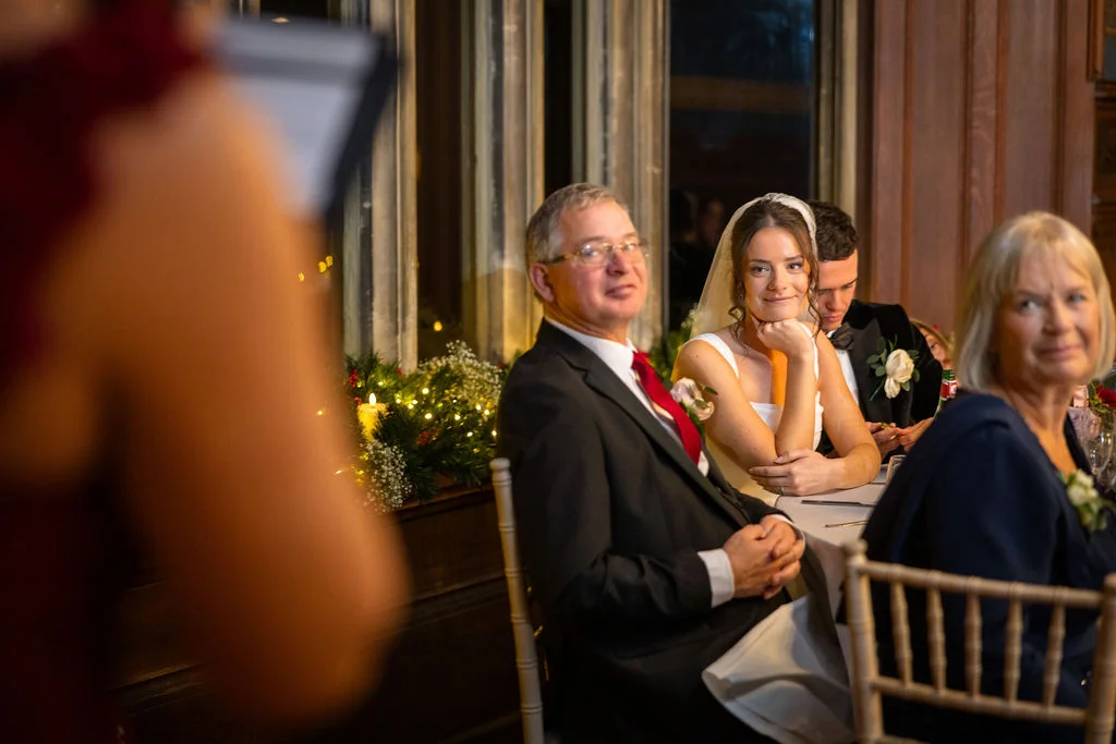 The bride and her family listen attentively during the wedding speeches at a candlelit reception dinner.