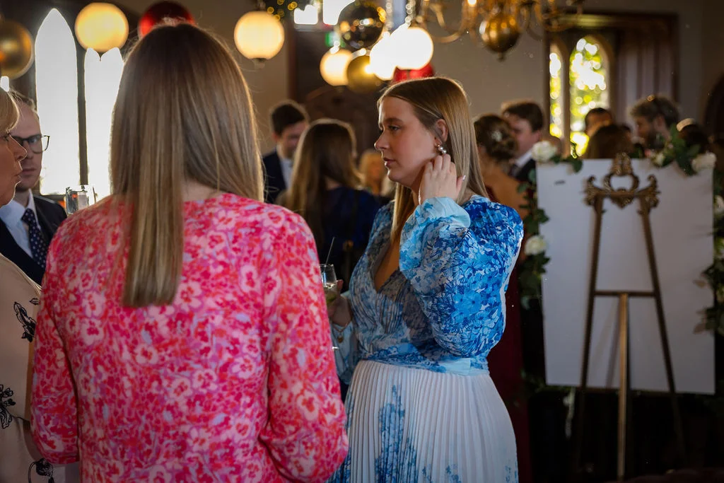 Wedding guests mingle during the drinks reception, with one guest wearing a striking blue and white floral dress.