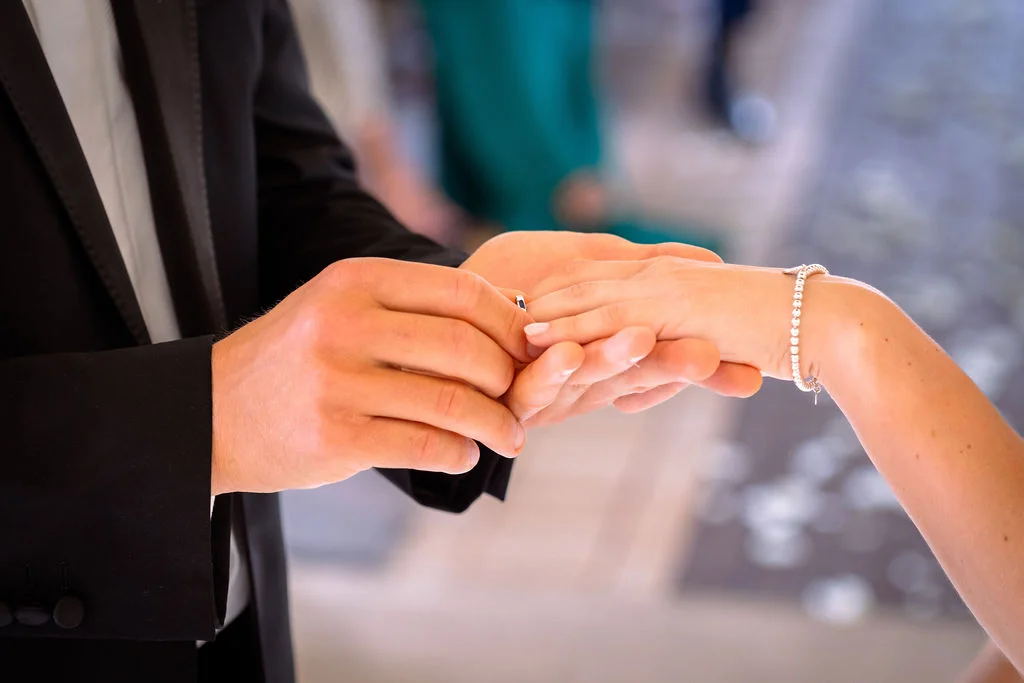 A man is putting a ring on a bride's hand.