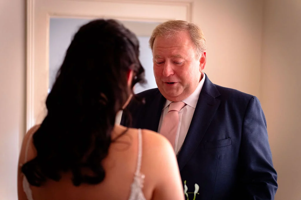 A father gazes emotionally at his daughter in her wedding dress during a private first look moment before the ceremony.