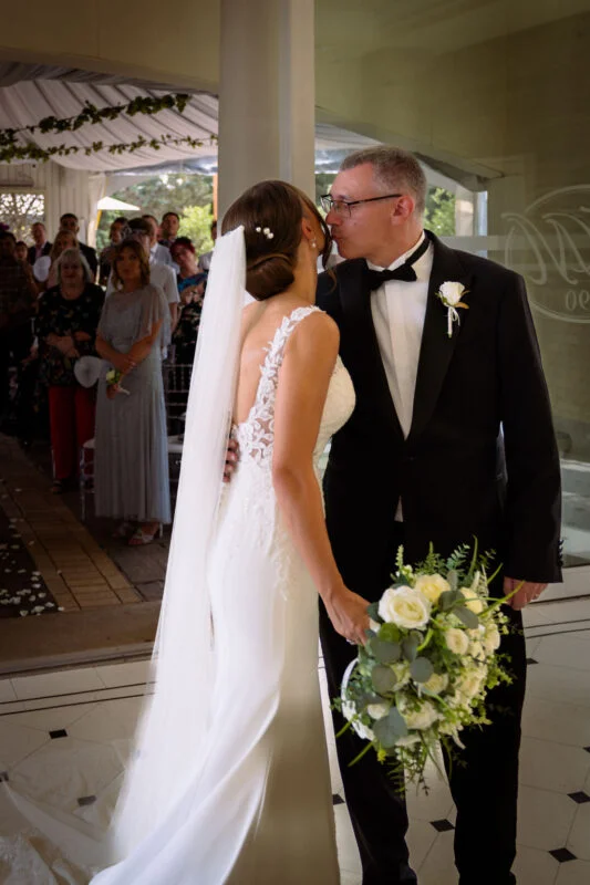 A bride and groom kissing in front of an audience.