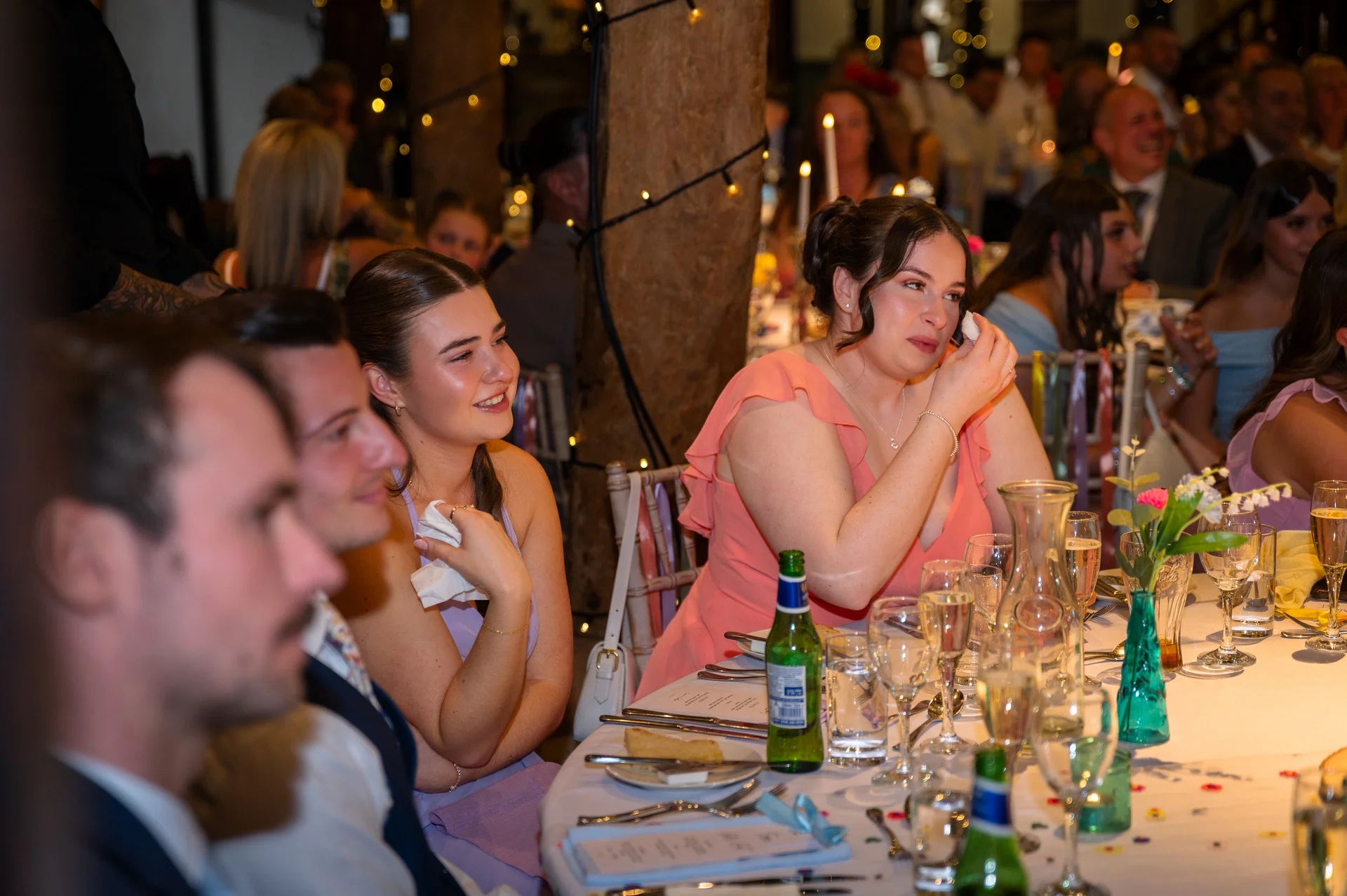 Emotional wedding guests are moved to tears and laughter during the speeches at a candlelit barn reception.
