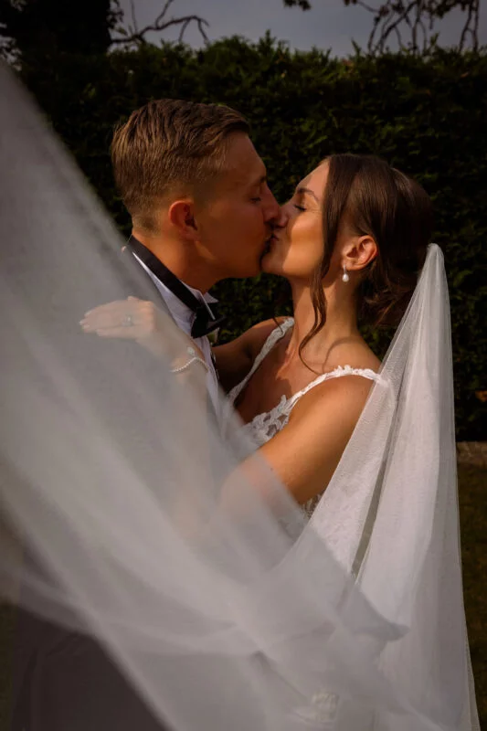 A bride and groom kissing under a veil.