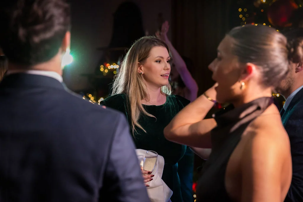 Wedding guests mingling and enjoying the evening reception under warm fairy light illumination.