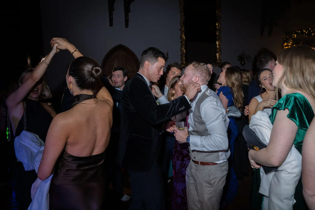Guests enjoy a lively evening reception on a packed dance floor, captured with direct flash photography inside a grand venue.