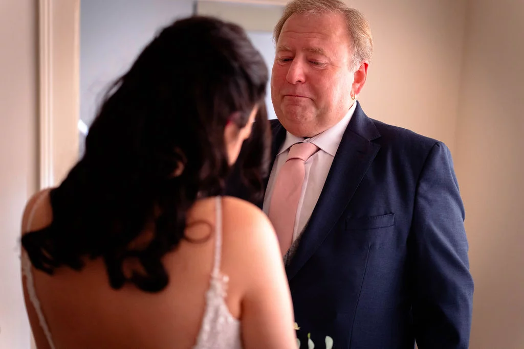 An emotional father of the bride looks tearfully at his daughter in her wedding dress during a morning first look.