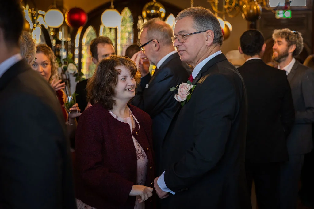Guests mingling warmly and smiling during a lively pub wedding reception filled with natural light.