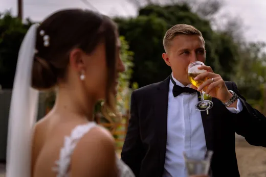 A bride and groom drinking a glass of beer.