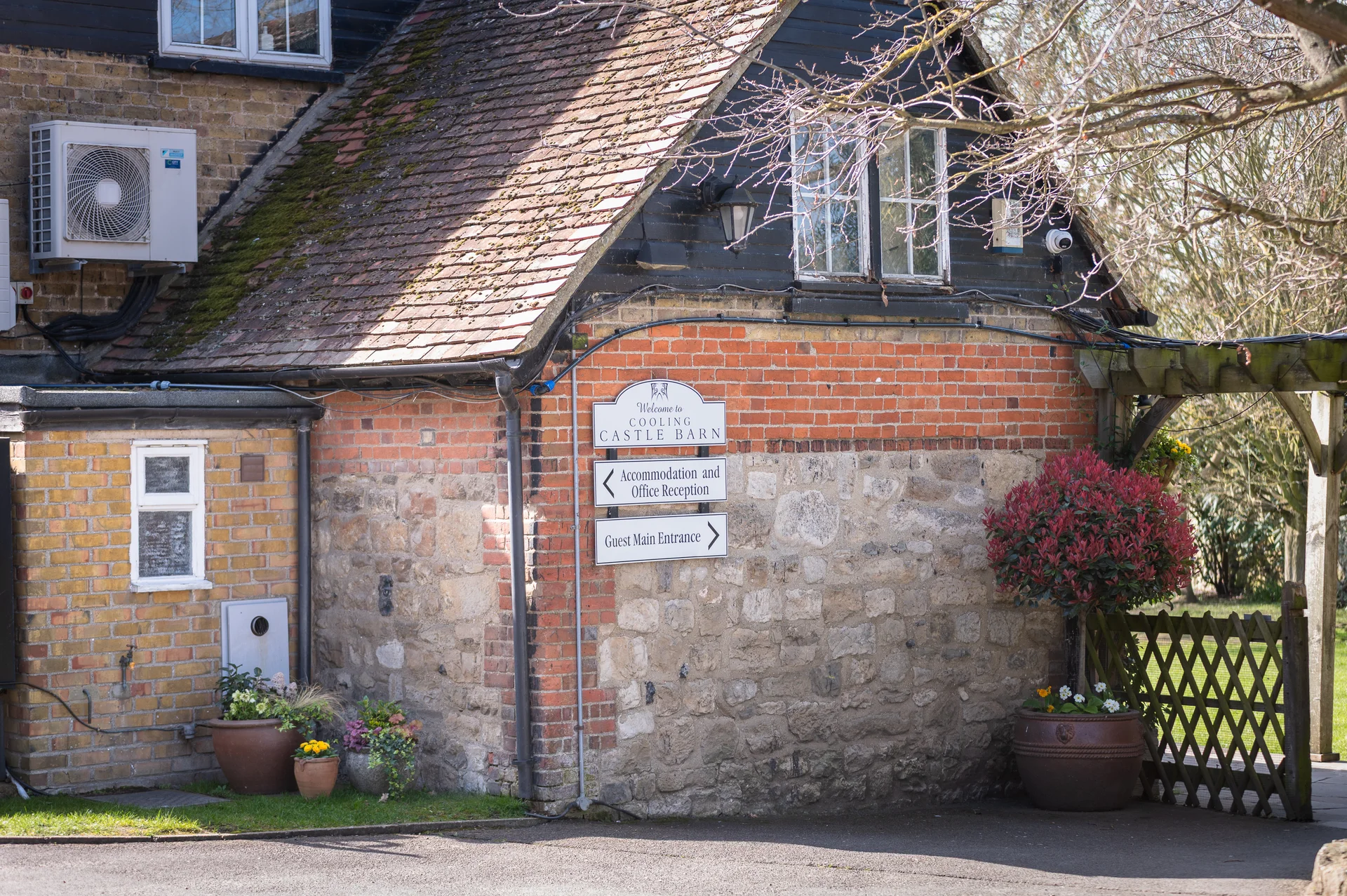 Directional signage points guests toward accommodation, office reception, and the main entrance at a rustic stone and brick barn wedding venue.
