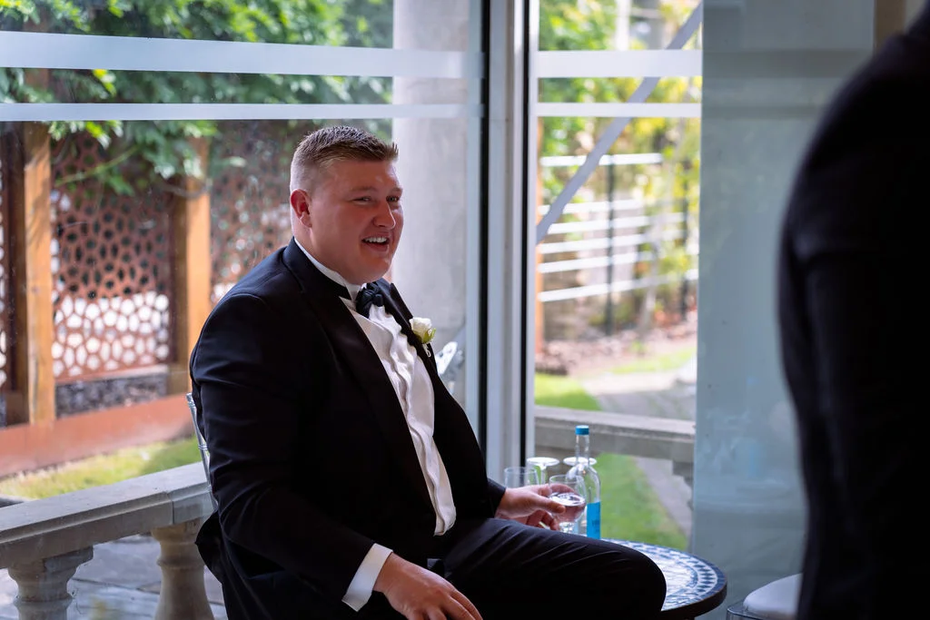 A man in a tuxedo sitting in front of a window.