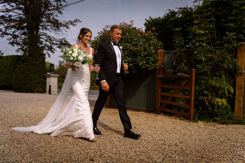 A bride and groom walking down a gravel path.