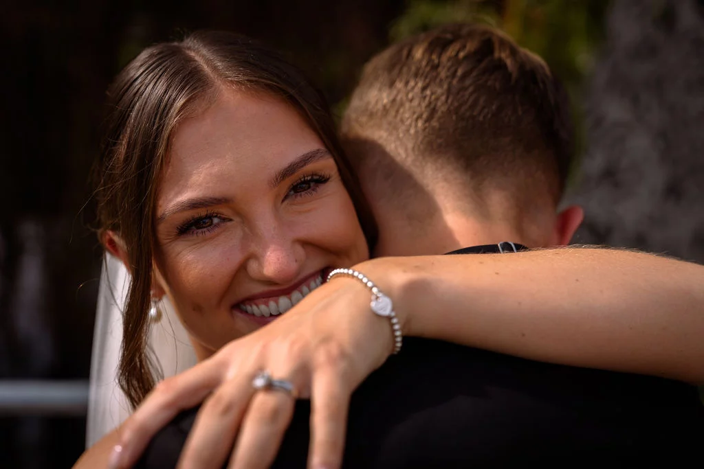 A bride and groom hugging in front of a waterfall.