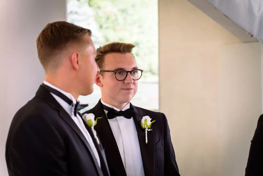 Two men in tuxedos looking at each other.