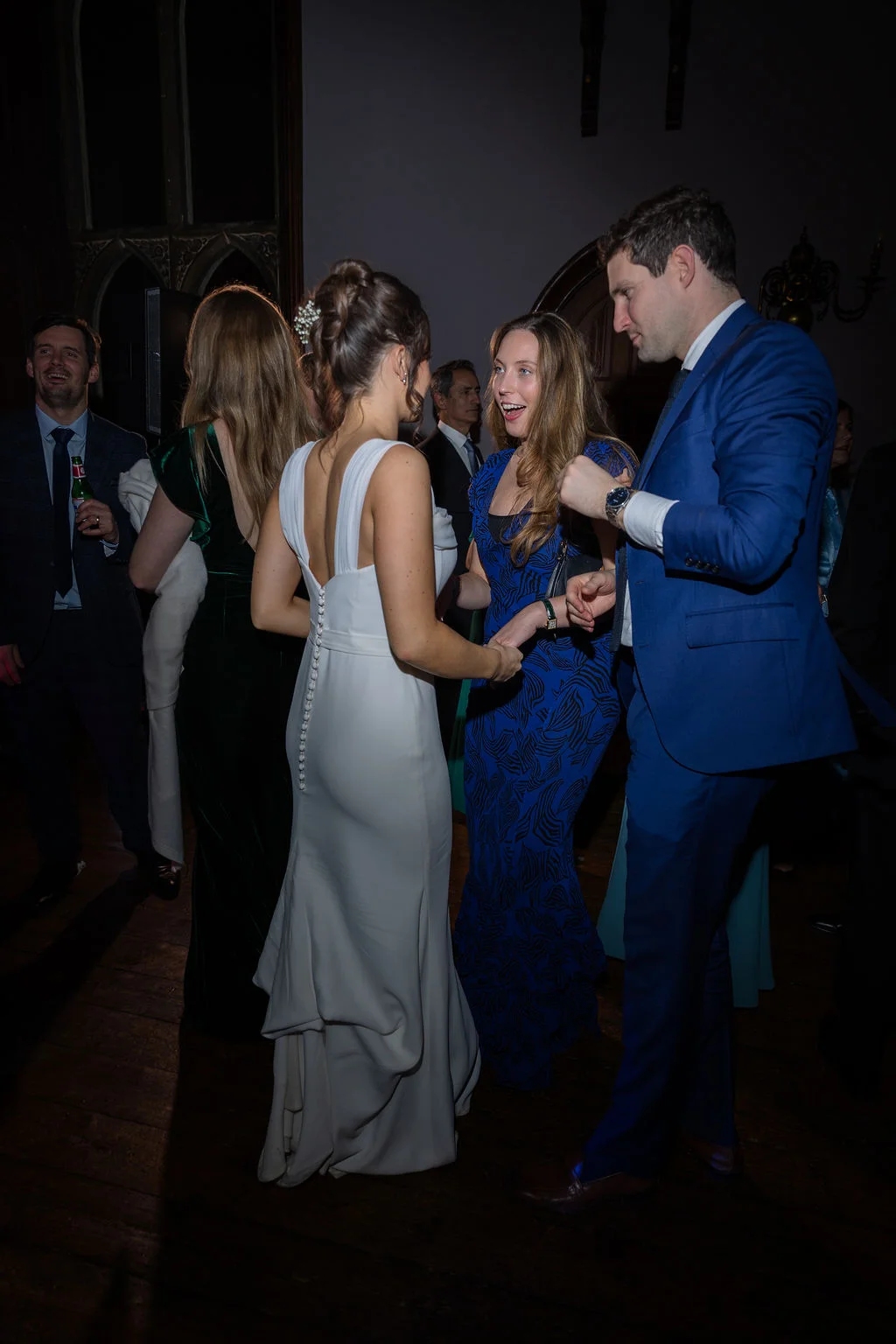 A bride in a white gown mingling with guests on the dance floor during an evening wedding reception.