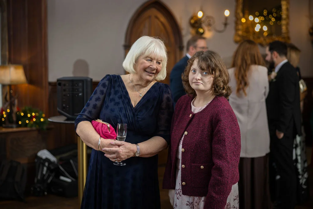 Two wedding guests enjoying a candid moment during the drinks reception inside an elegant historic venue.