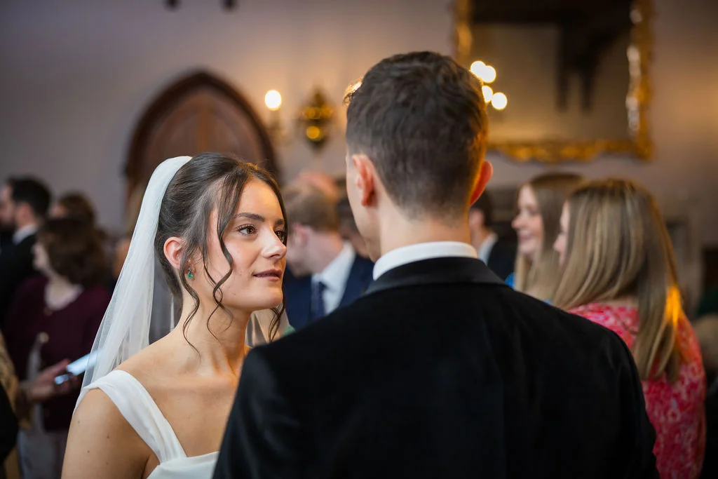 The bride gazes lovingly at her groom in a classic country house setting during an intimate indoor wedding ceremony.