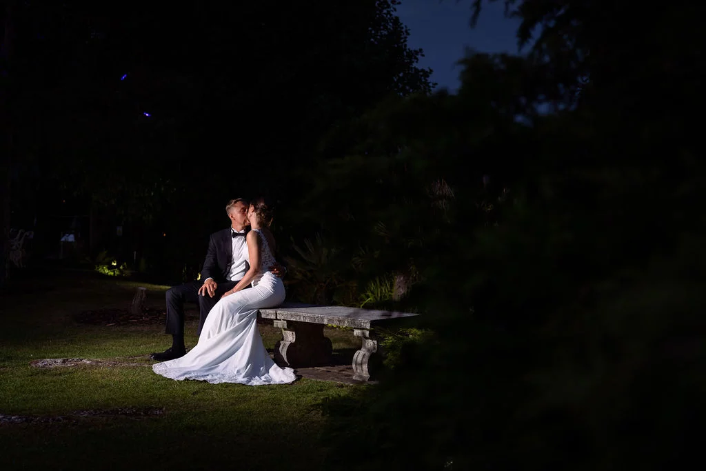 A bride and groom sitting on a bench at night.