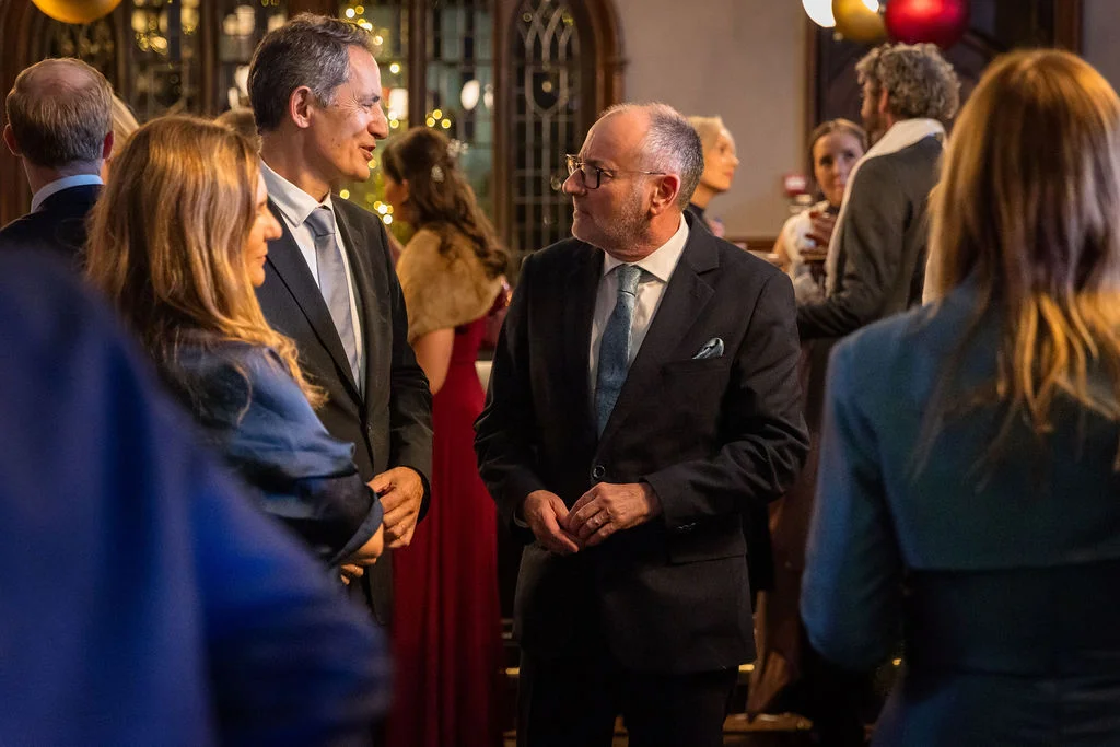 Dressed-up wedding guests mingle and converse naturally inside an elegant evening reception venue.