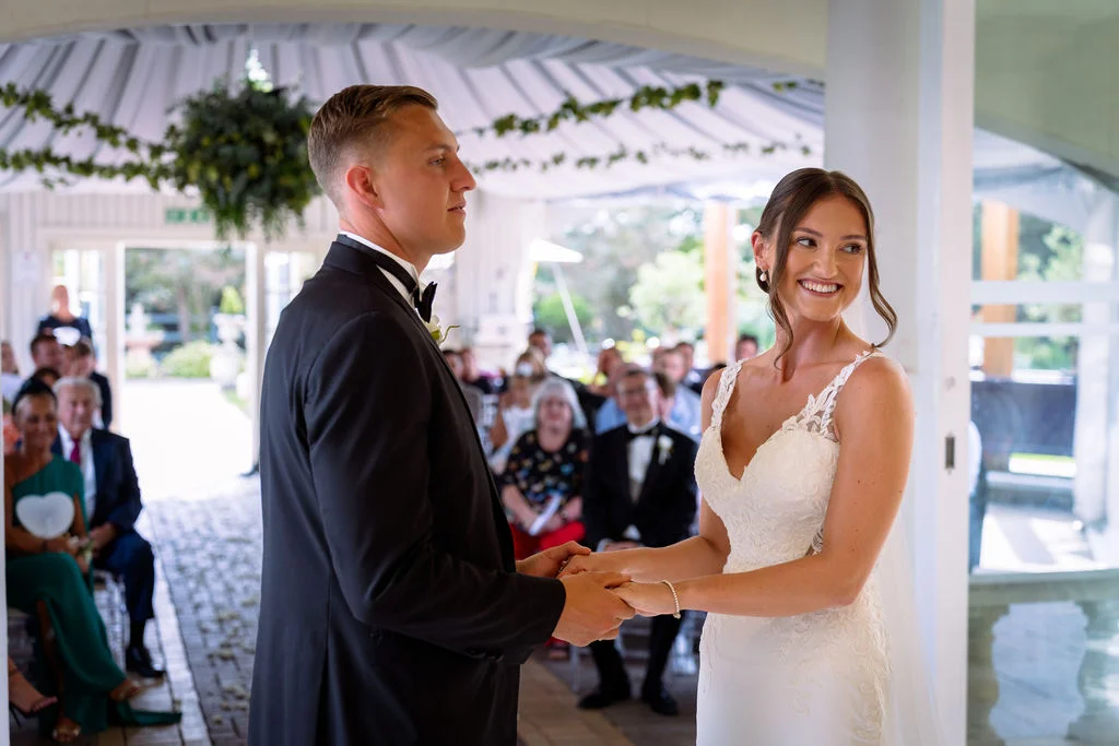 A bride and groom holding hands during their wedding ceremony.