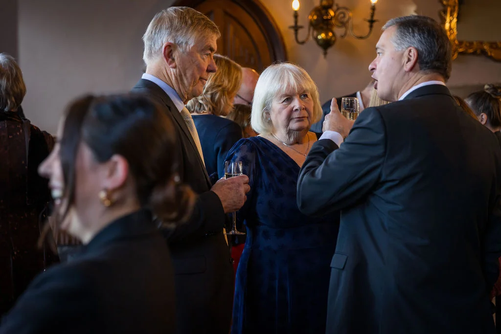 Wedding guests smiling and chatting together during the drinks reception inside an elegant venue.