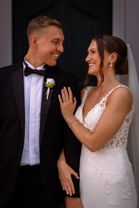A bride and groom smiling in front of a door.