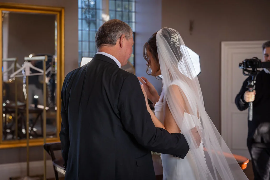An emotional father of the bride shares a tender first look moment with his daughter in her wedding gown and veil.