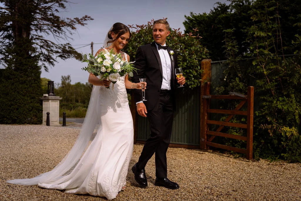 A bride and groom walking down a driveway.