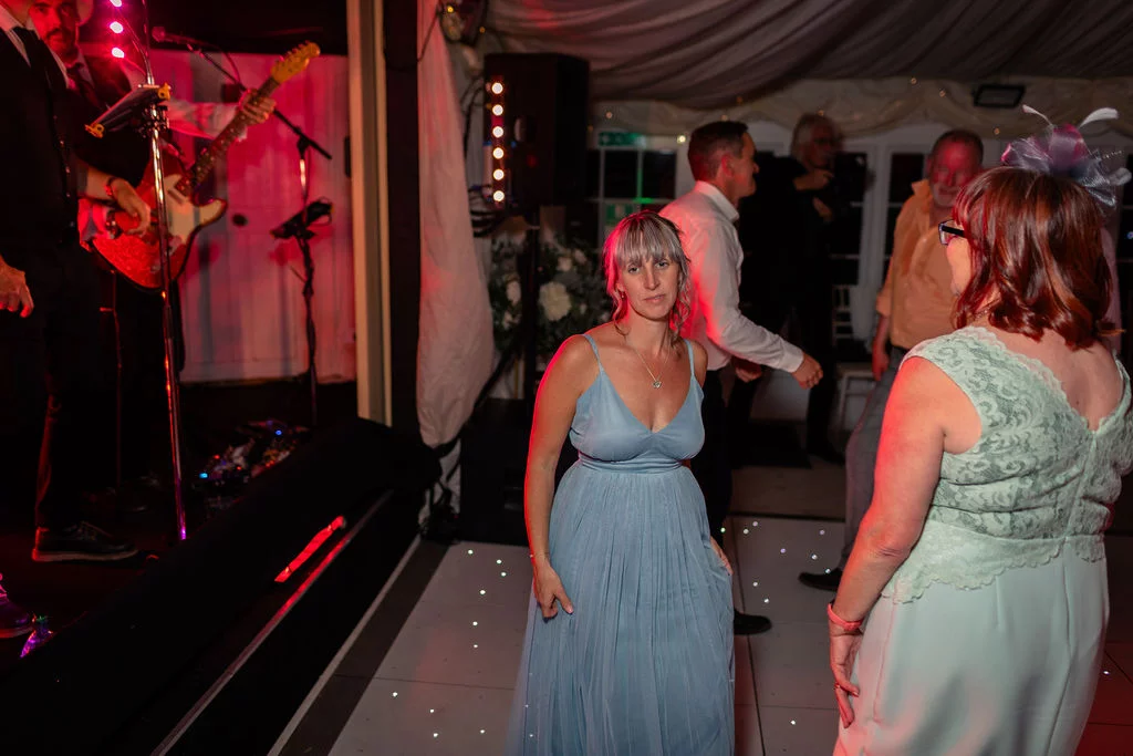 Guests enjoy themselves on a lighted dance floor during the evening reception while a live band plays nearby.