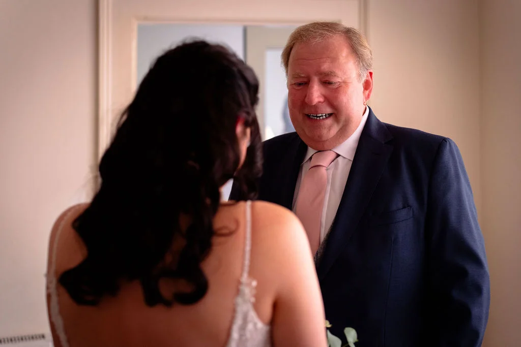 An emotional father of the bride looks on with tears in his eyes as he shares a special first look moment with his daughter on the morning of the wedding.