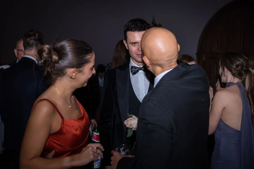 Wedding guests mingling and chatting candidly during an evening reception with warm indoor lighting.
