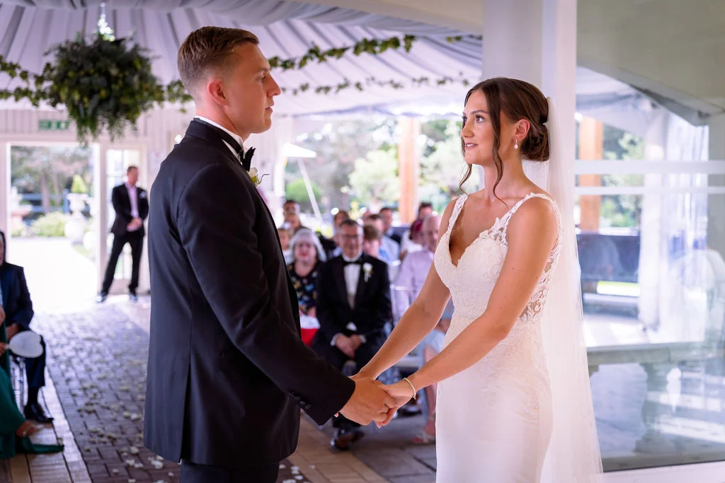 A bride and groom holding hands during their wedding ceremony.