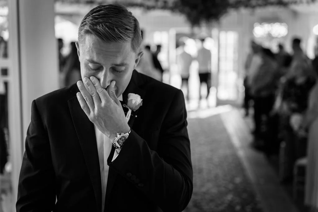 A groom wiping his face as he walks down the aisle.