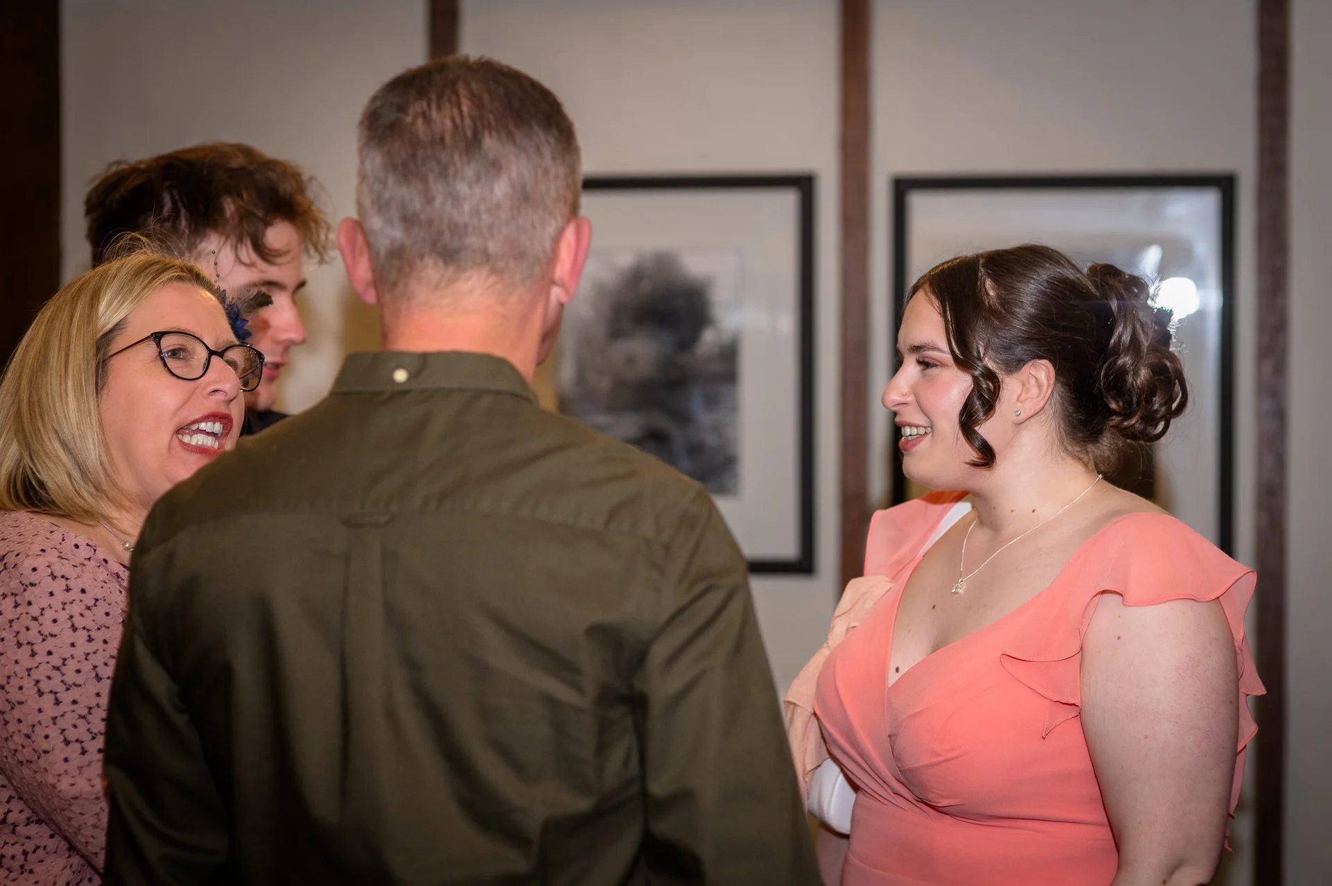 Wedding guests mingling and smiling during a relaxed reception celebration indoors.