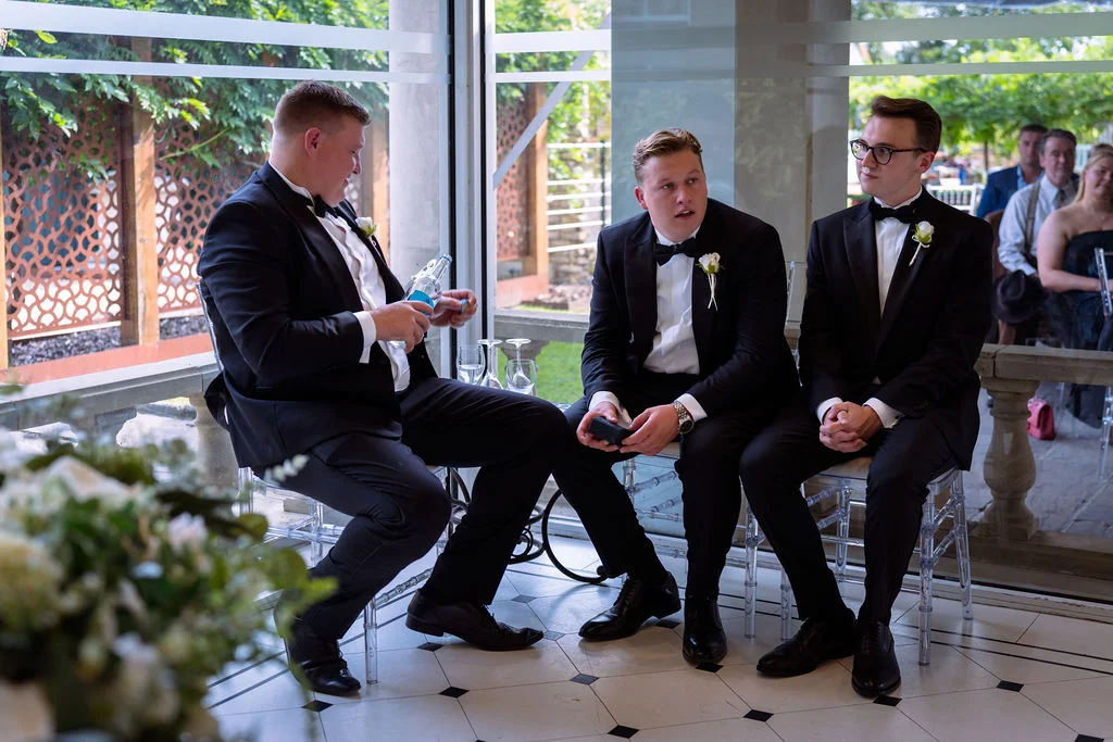 A group of men in tuxedos sitting in a room.
